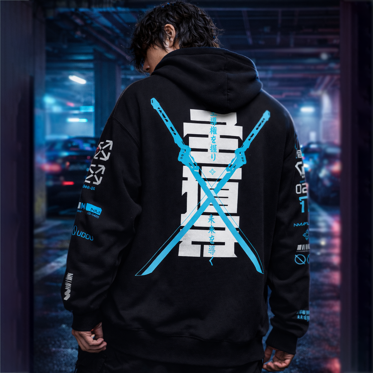 Person wearing a black hoodie with blue and white designs in an urban setting