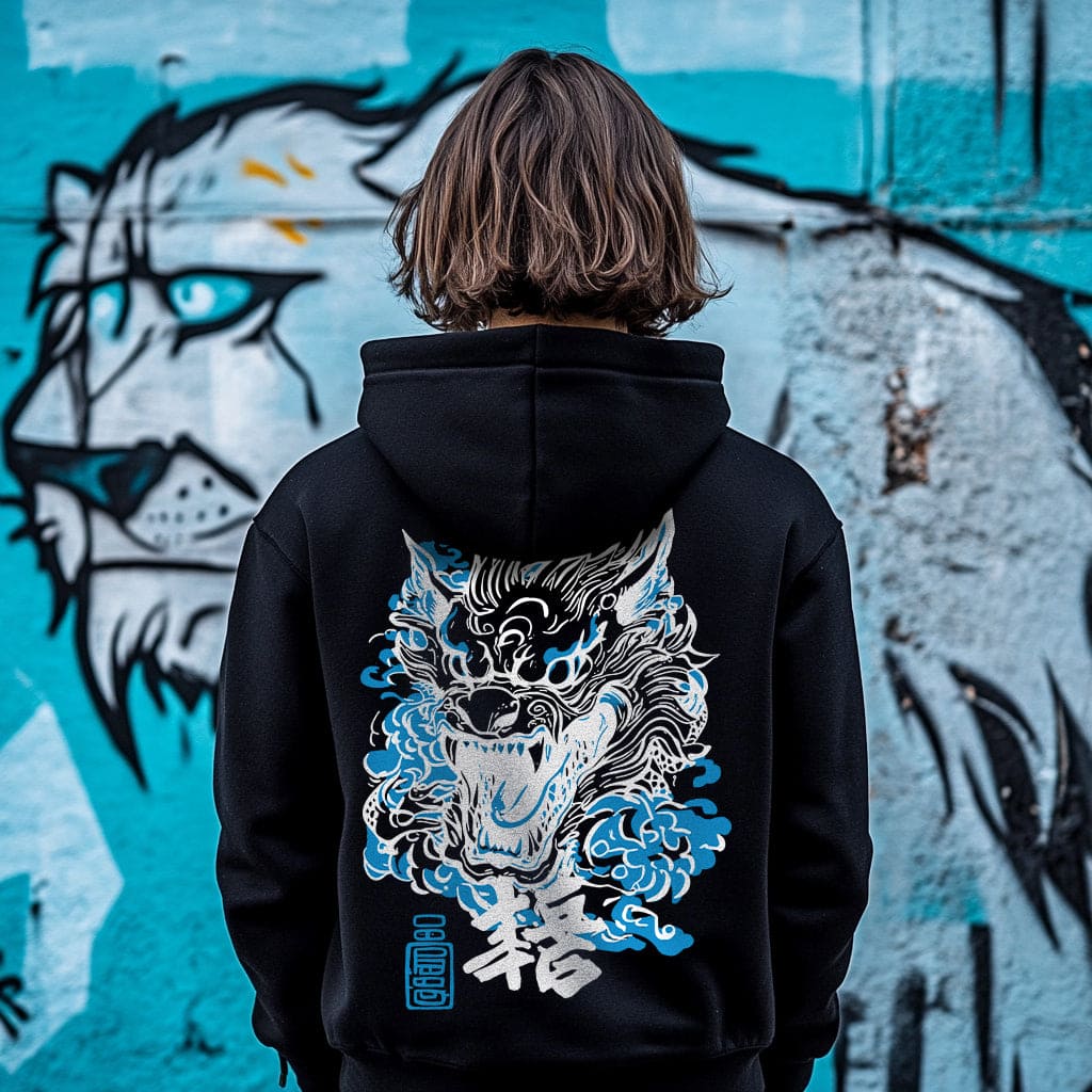 Person wearing a black hoodie with a wolf design in front of a graffiti wall.