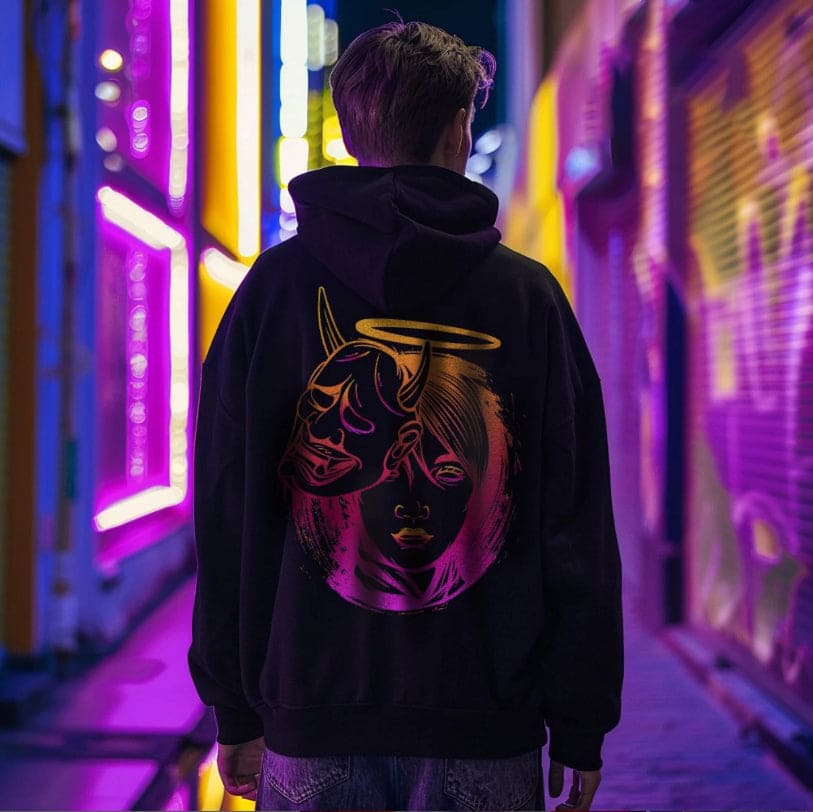 Person wearing a black hoodie with a colorful design in a neon-lit urban setting